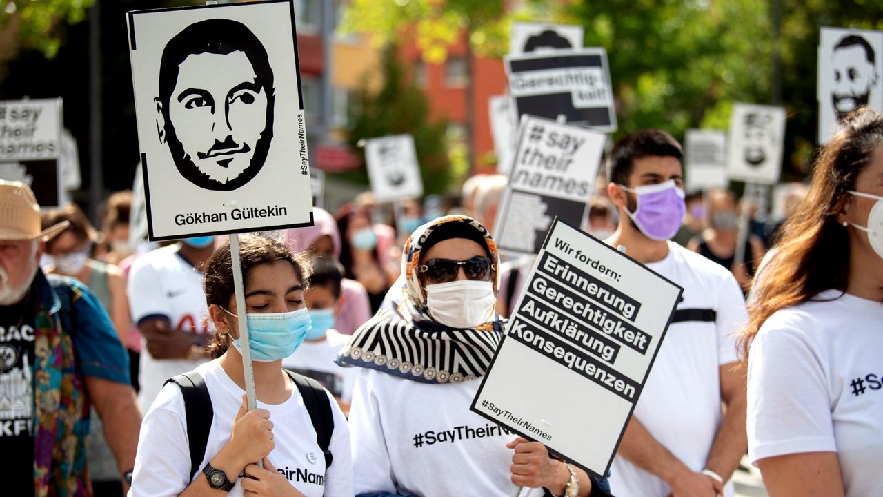 Mehrere hundert Menschen halten bei der offiziellen Gedenkveranstaltung zu den rassistisch motivierten Anschlägen in Hanau am 22.08.2020 Schilder mit den Fotos von Opfern in den Händen.