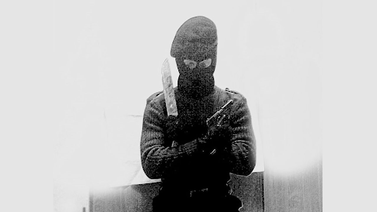 Ein Mitglied der mutmaßlich rechtsextremen Gruppe aus Kankaanpää posiert mit Sturmhaube, Messer und Pistole.