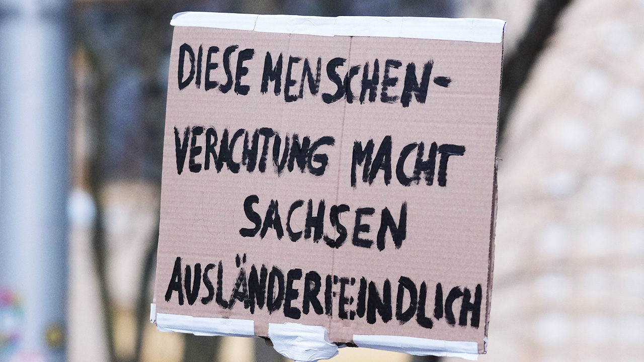 Eine Teilnehmerin einer Kundgebung hält ein Schild mit der Aufschrift „Diese Menschenverachtung macht Sachsen ausländerfeindlich“. Mit einer Demonstration sollte gegen die ursprünglich geplante Abschiebung von Pham Phi Son und seiner Familie protestiert werden.