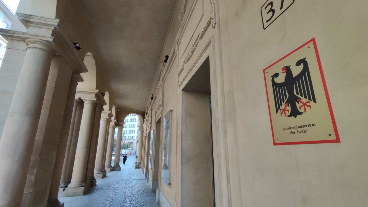 Säulengang aus dem 19. Jahrhundert, links Säulen, rechts Türen, vorne ein Schild mit dem Bundesadler darauf, Aufschrift "Bundesministerium für Justiz".
